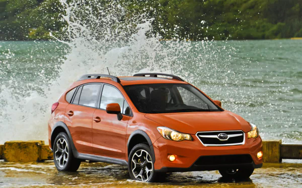 Subaru Crosstrek parked by water with waves splashing around, serving as a vibrant HD desktop wallpaper.