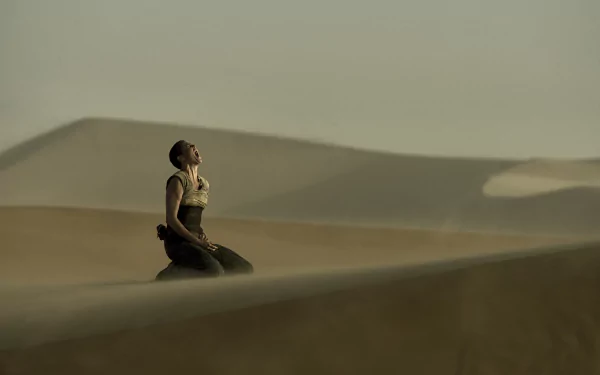 Imperator Furiosa, portrayed by Charlize Theron, kneels in a vast desert landscape from the movie *Mad Max: Fury Road*, captured in stunning HD for a dynamic wallpaper background.