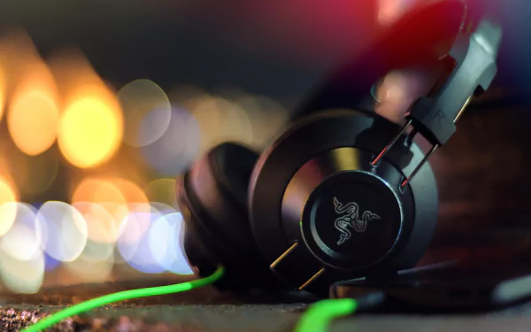 A high-definition desktop wallpaper featuring Razer headphones, showcasing sleek design and vibrant green accents against a blurred, colorful background.
