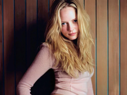 HD PC desktop wallpaper featuring a woman with long blonde hair and a soft pink top, identified as Marley Shelton, standing against a vertical wooden panel background.