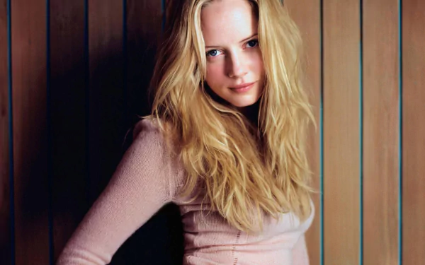HD PC desktop wallpaper featuring a woman with long blonde hair and a soft pink top, identified as Marley Shelton, standing against a vertical wooden panel background.