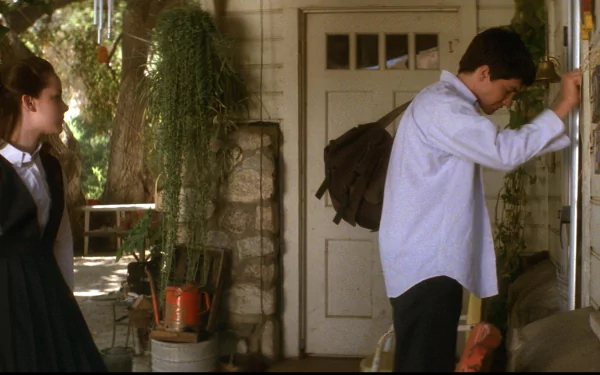 HD desktop wallpaper featuring Jena Malone and Jake Gyllenhaal in a scene from the movie Donnie Darko. The image depicts them outside a house, with Jake leaning on the front door.