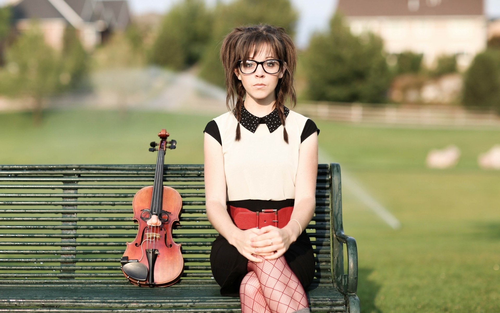 2K Quad HD PC desktop wallpaper and background — music-themed portrait of a female violinist seated on a park bench with her violin at her side, soft green lawn behind her.
