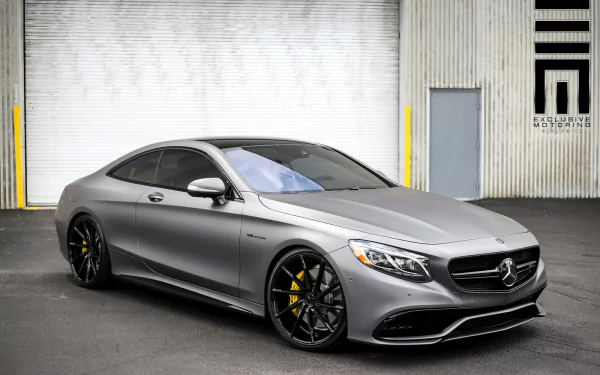 HD PC desktop wallpaper featuring a sleek silver Mercedes-Benz coupe parked in front of an industrial building with modern architectural elements.