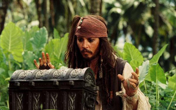 Jack Sparrow, played by Johnny Depp, appears intrigued as he examines a chest surrounded by lush greenery in a scene from *Pirates of the Caribbean: Dead Man's Chest*.