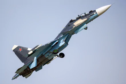 HD wallpaper featuring a military Sukhoi Su-30 jet in flight against a clear sky background.