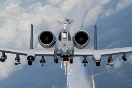 HD desktop wallpaper showcasing a Fairchild Republic A-10 Thunderbolt II aircraft in flight, firing flares against a cloudy sky backdrop, highlighting its military design.