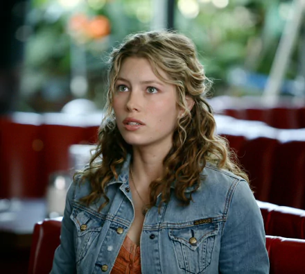 HD PC desktop wallpaper: cinematic movie-style still of a young woman with wavy blonde hair in a denim jacket, startled expression while seated in a diner booth.