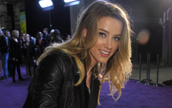 A high-definition desktop wallpaper featuring celebrity Amber Heard, smiling and engaging with the camera amid a vibrant event backdrop.
