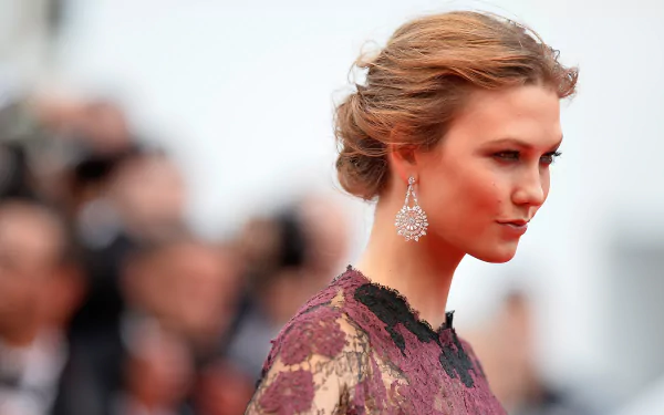 HD PC desktop wallpaper featuring celebrity Karlie Kloss in an elegant lace dress and statement earrings, captured in a side profile at a formal event.