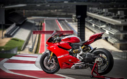 HD PC desktop wallpaper featuring a Ducati 1199 motorcycle parked on a racetrack with racing stands in the background.