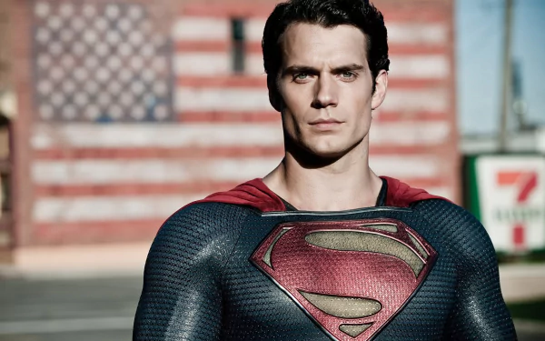 Henry Cavill as Superman in Man of Steel, striking a powerful pose with an American flag backdrop, featured as an HD wallpaper for fans of the iconic movie.