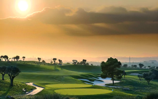 HD desktop wallpaper of a sunlit golf course featuring a green fairway, winding path, scattered trees, and a dramatic sky with clouds at sunrise or sunset.