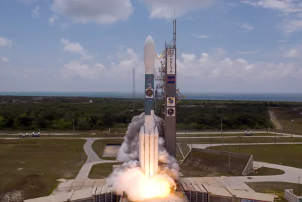 Delta II rocket launches from Cape Canaveral, NASA site, captured in HD as it ascends with bright flames and smoke against a partly cloudy sky.