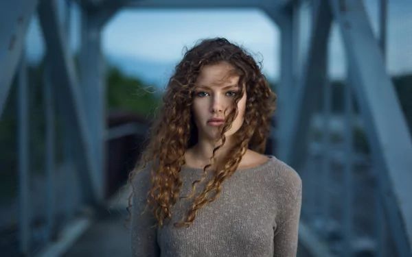 Close-up portrait of a brunette woman with curly hair and blue eyes, captured in 4K Ultra HD as a PC desktop wallpaper.