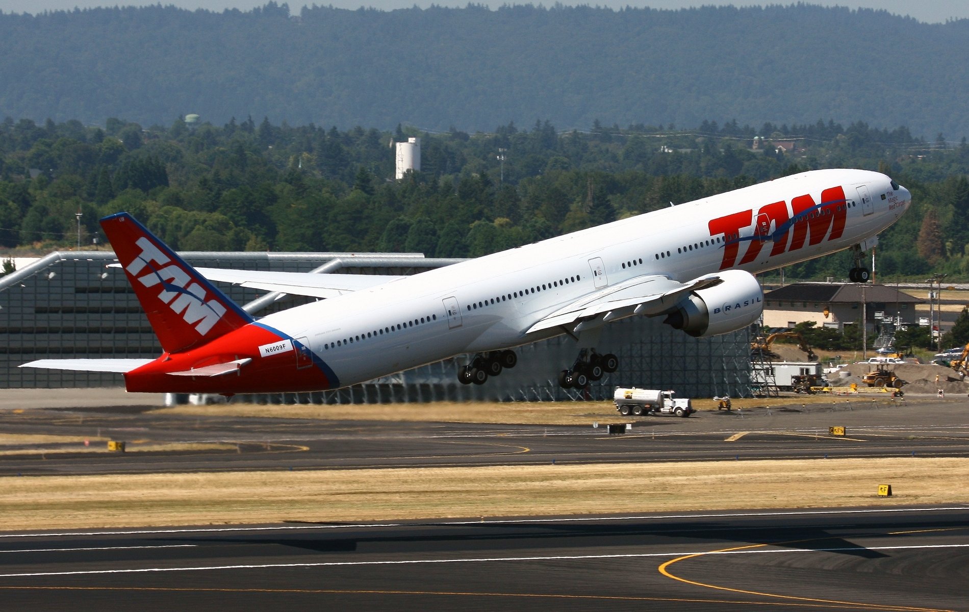 A Boeing 777 jet takes off against a clear blue sky, showcasing its dynamic ascent, captured as an HD desktop wallpaper and background.
