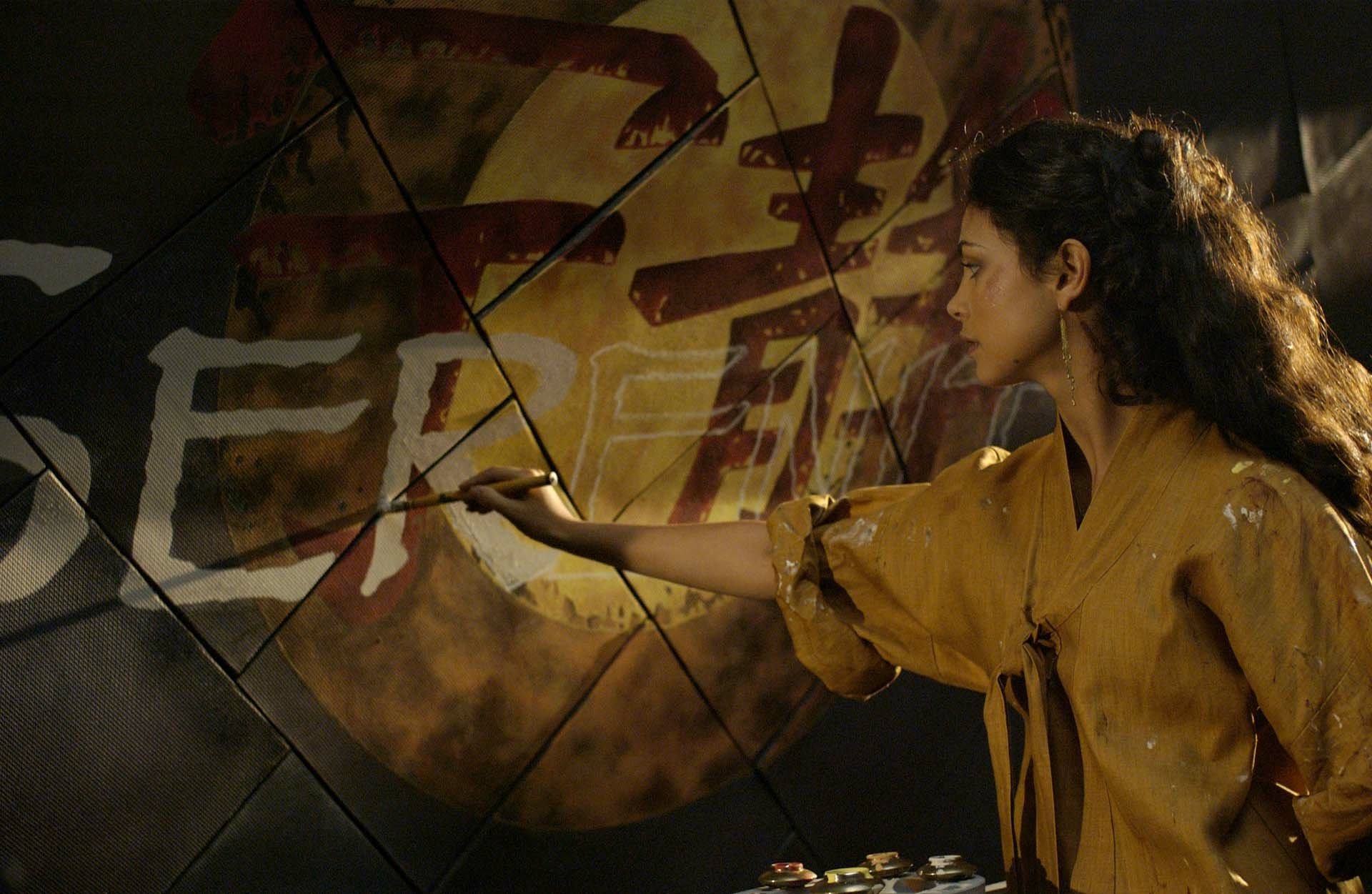 Woman painting the Serenity (2005) emblem on a metal wall — cinematic movie still presented as an HD PC desktop wallpaper/background.