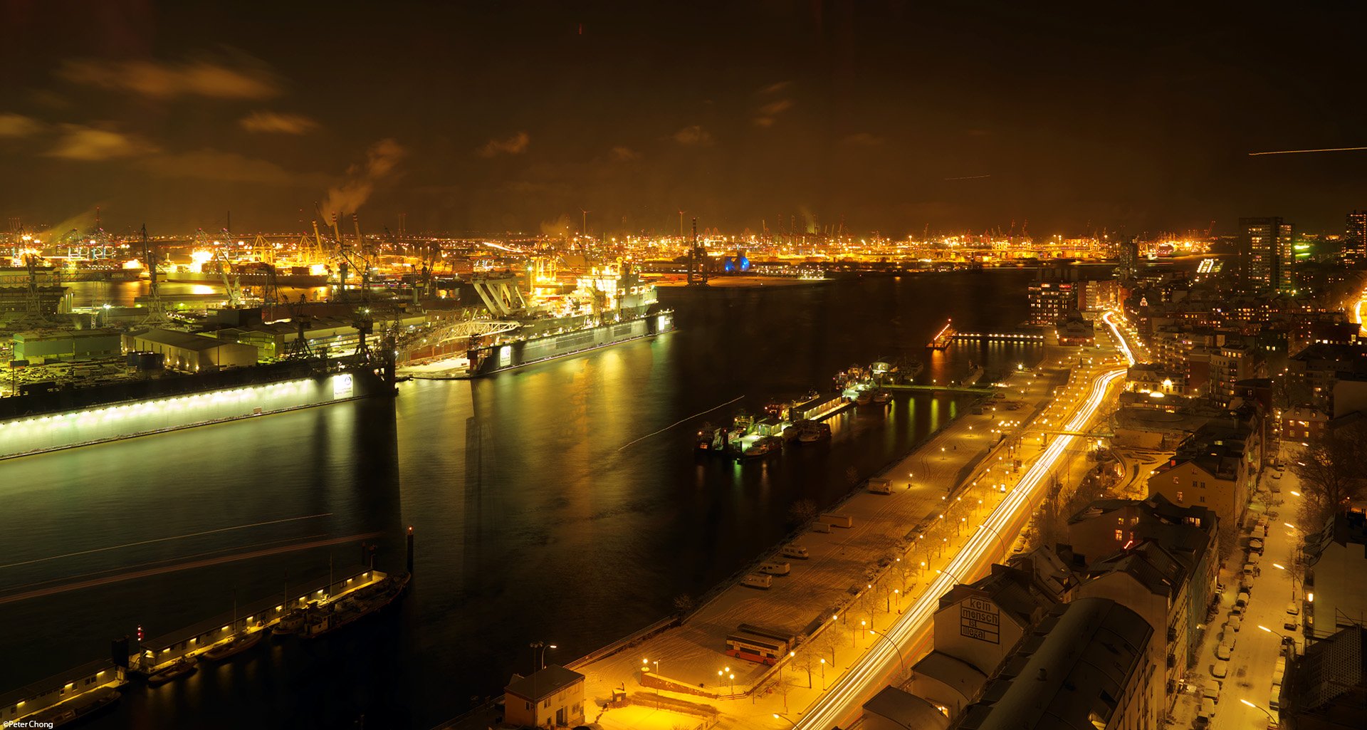 Nighttime cityscape of Hamburg harbor with illuminated docks and industrial structures, captured in a high-definition man-made environment.