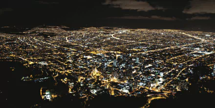 Aerial view of man-made cityscape of Bogotá illuminated at night, captured in high-definition for a PC desktop wallpaper and background.