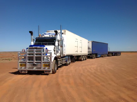 HD desktop wallpaper featuring a Western Star road train vehicle parked on a vast, flat desert landscape under a clear blue sky.