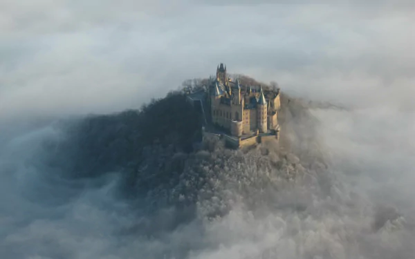 Aerial view of the man-made Hohenzollern Castle rising above dense fog, captured in HD quality for a stunning PC desktop wallpaper background.