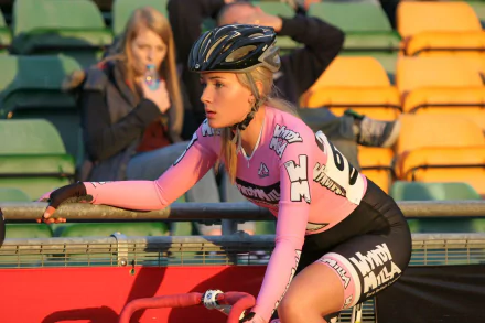 HD desktop wallpaper featuring cyclist Puck Moonen in pink and black gear, captured during a sports event with colorful stadium seating in the background.