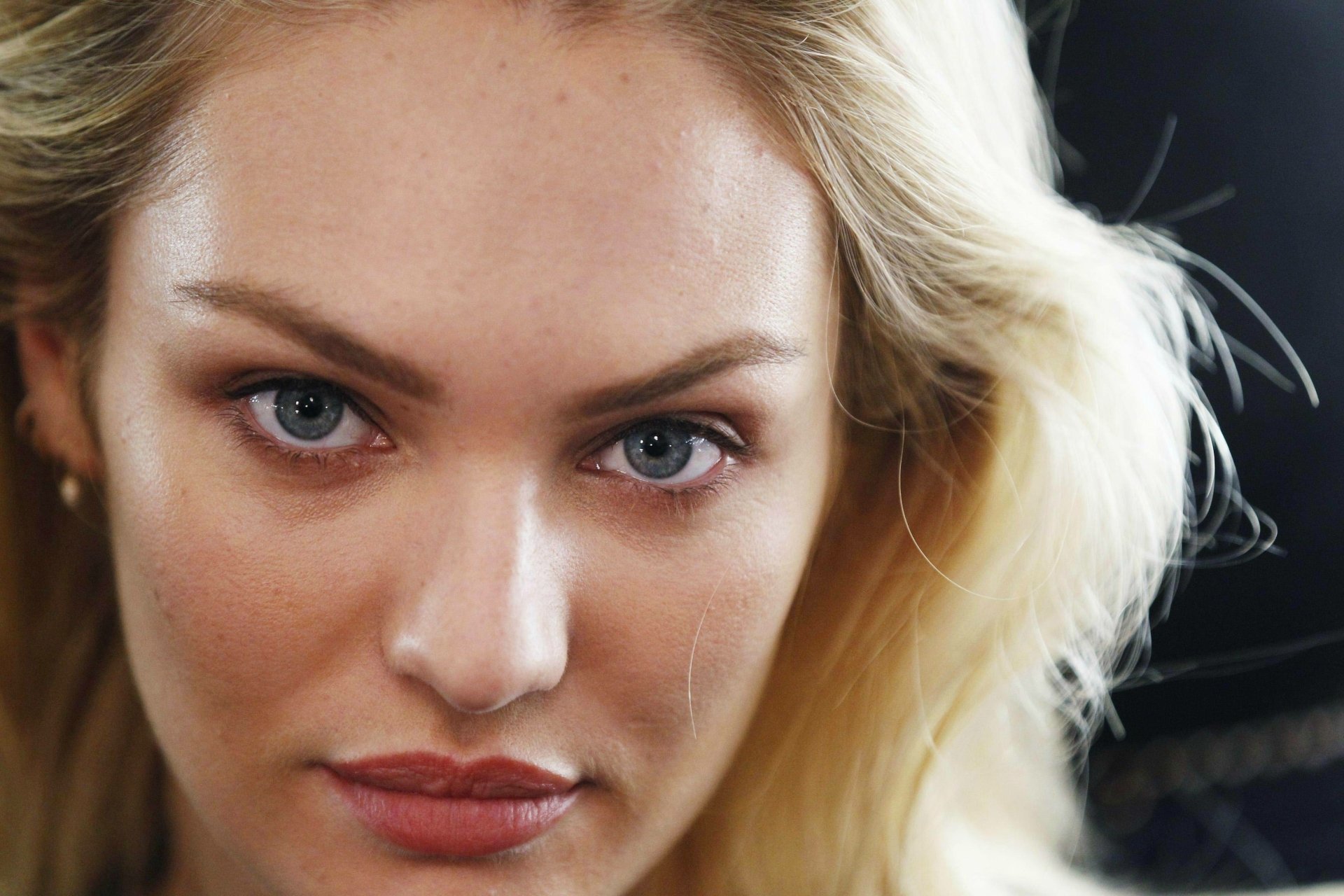 Close-up HD desktop wallpaper of woman Candice Swanepoel with blonde hair, blue eyes, and natural makeup against a dark background.