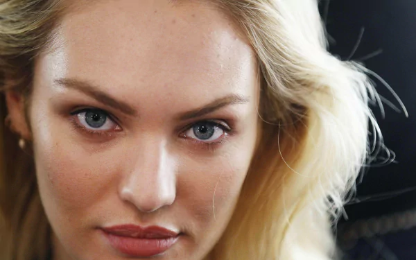 Close-up HD desktop wallpaper of woman Candice Swanepoel with blonde hair, blue eyes, and natural makeup against a dark background.