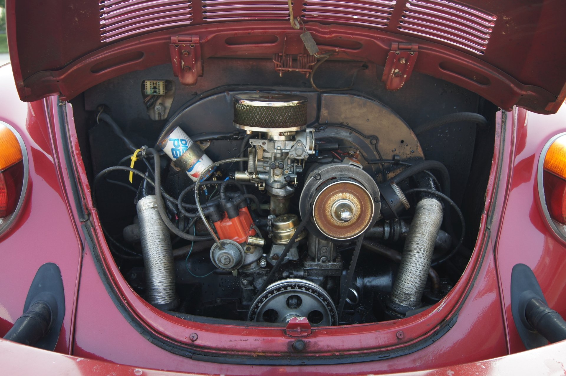 Rear-mounted engine of a red Volkswagen Beetle with hood up, detailed mechanical components, presented as a 4K Ultra HD PC desktop wallpaper/background.
