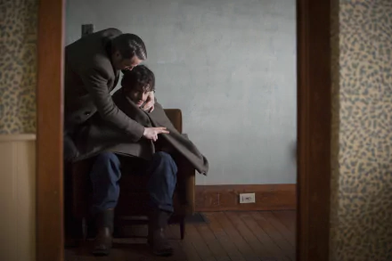 Moody TV-drama scene: one man leans over another seated in a sparse, dim room; atmospheric 2K Quad HD PC desktop wallpaper/background.