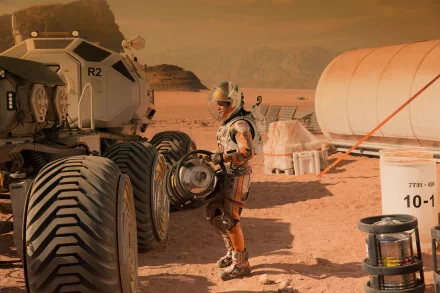HD desktop wallpaper featuring Matt Damon in character from the movie The Martian, standing next to a rover in a Mars-like desert environment.