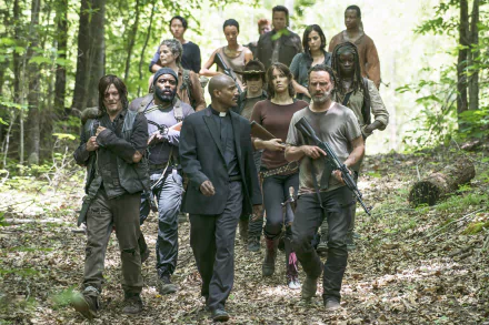 A group of characters from the TV show The Walking Dead walks through a forest, showcasing a tense, post-apocalyptic atmosphere in this HD desktop wallpaper.