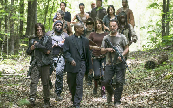 A group of characters from the TV show The Walking Dead walks through a forest, showcasing a tense, post-apocalyptic atmosphere in this HD desktop wallpaper.
