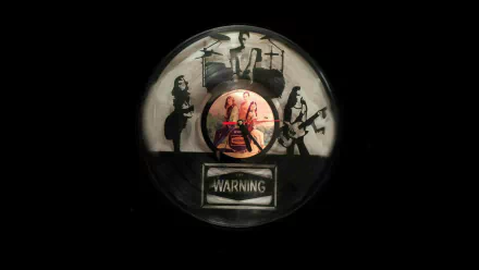 HD PC desktop wallpaper featuring The Warning band members with their instruments silhouetted around a central, colorful band photo and a warning label beneath.