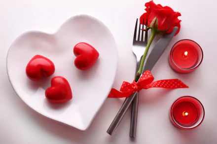 HD wallpaper featuring a romantic Valentine's Day scene with a red rose, a heart-shaped plate with red heart decorations, a fork and knife tied with a ribbon, and two red candles.