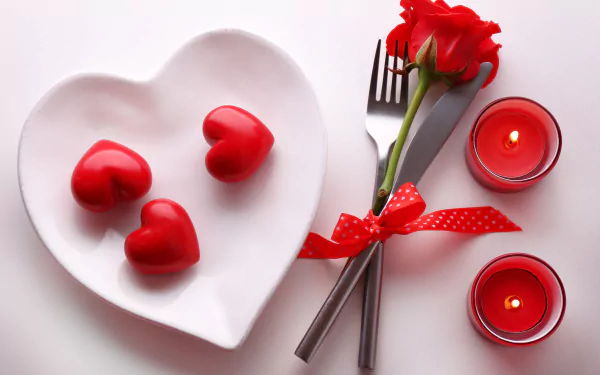 HD wallpaper featuring a romantic Valentine's Day scene with a red rose, a heart-shaped plate with red heart decorations, a fork and knife tied with a ribbon, and two red candles.
