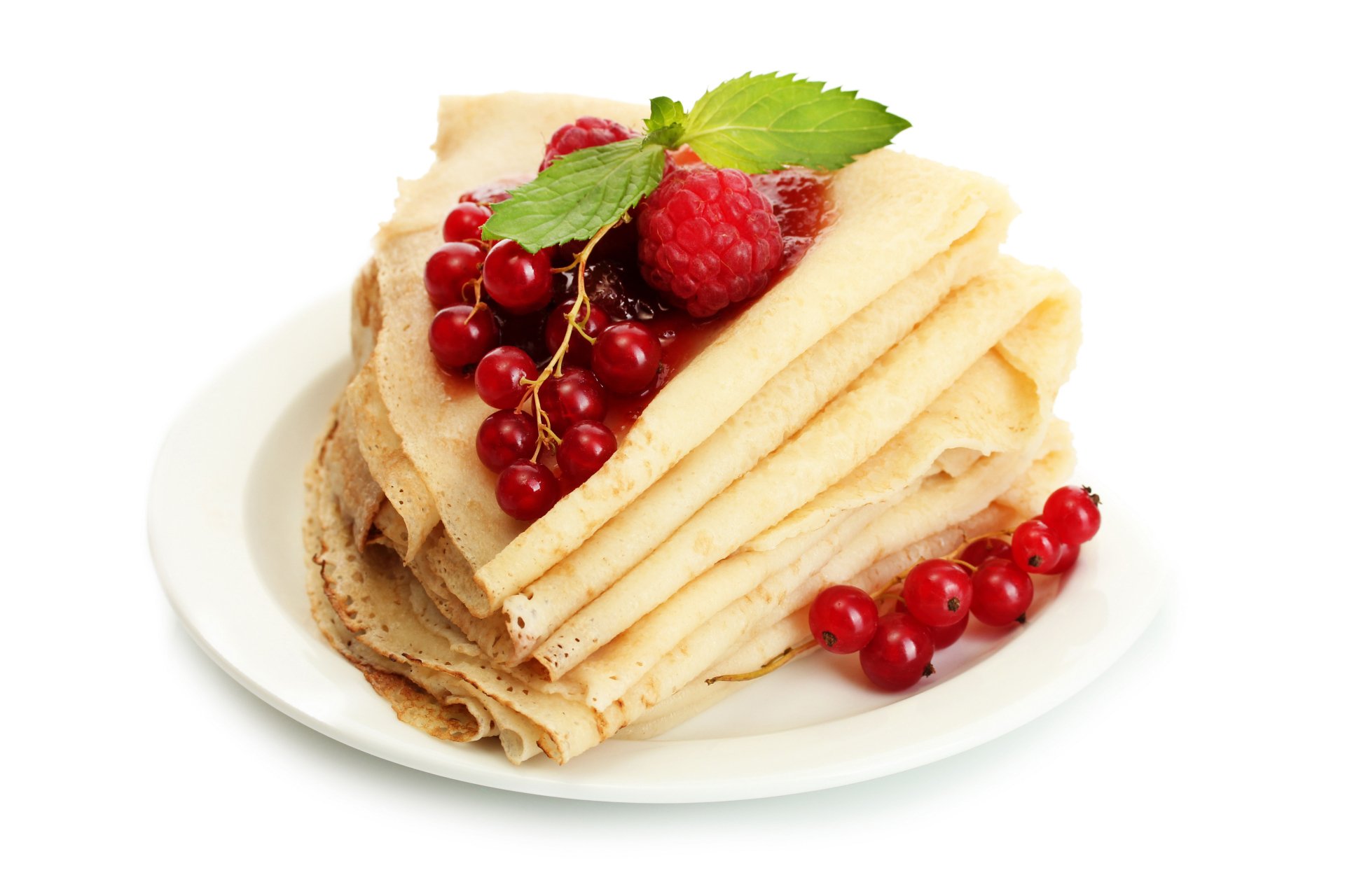 Stack of folded crêpes garnished with fresh raspberries, red currants, and mint leaves on a white plate, captured in 4K Ultra HD.