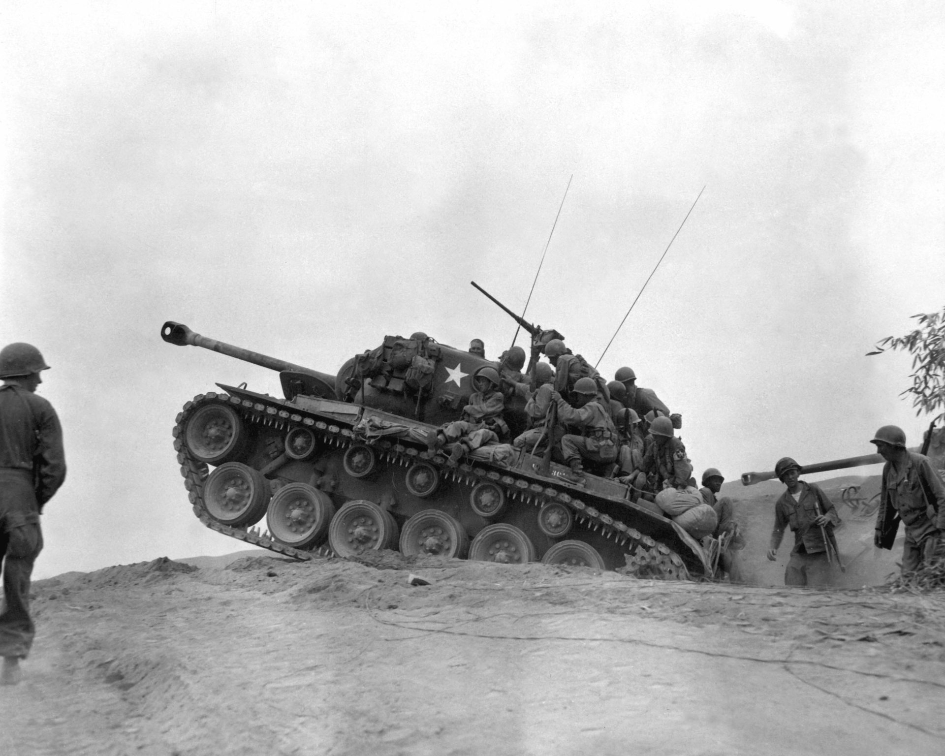 Black and white World War II military scene showing soldiers riding a tank climbing a hill, captured in high detail as an HD PC desktop wallpaper and background.
