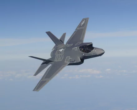 Lockheed Martin F-35 Lightning II stealth fighter banking above clouds, military 2K Quad HD PC desktop wallpaper and background.