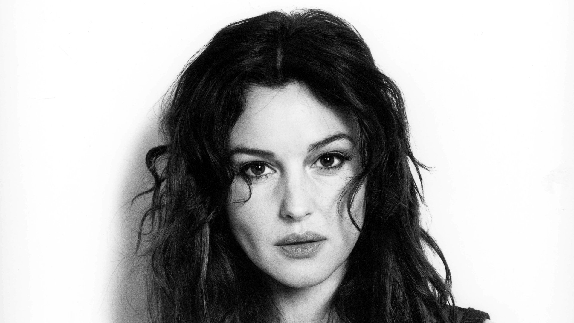 Black and white 4K Ultra HD desktop wallpaper featuring a close-up portrait of Monica Bellucci with wavy hair and a serious expression.