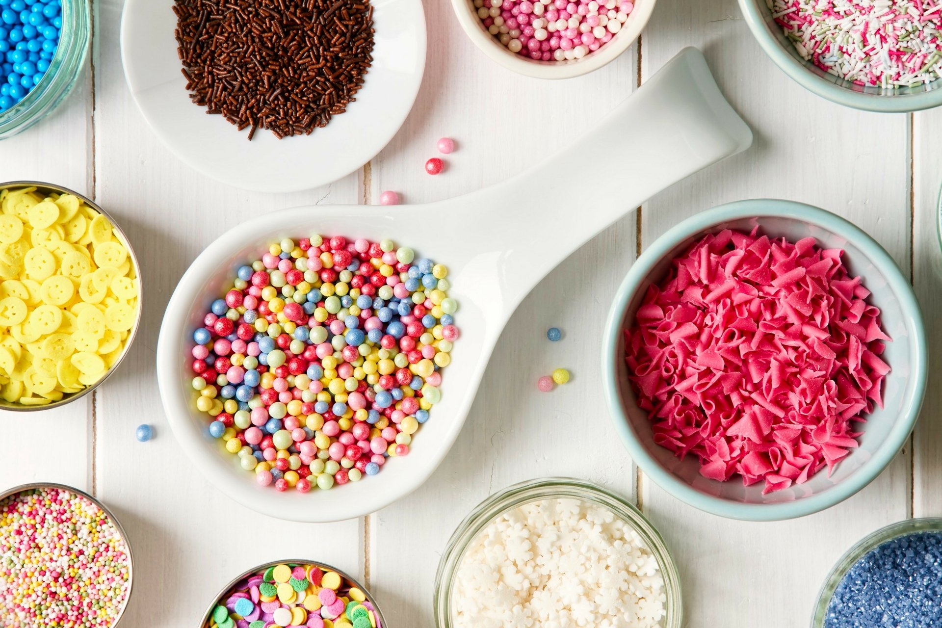 4K Ultra HD PC desktop wallpaper: food candy—overhead view of colorful candy sprinkles and confection toppings in bowls and a spoon on a white wooden background.
