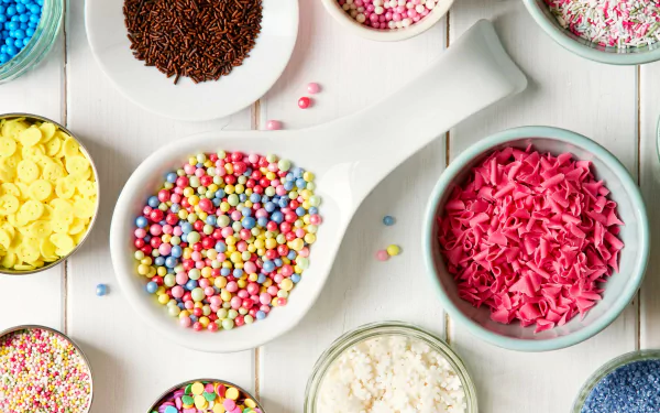 4K Ultra HD PC desktop wallpaper: food candy—overhead view of colorful candy sprinkles and confection toppings in bowls and a spoon on a white wooden background.
