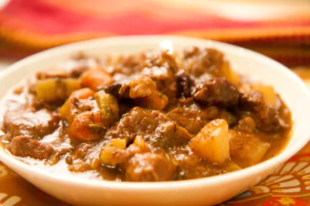 Hearty beef-and-vegetable stew in a bowl, rich brown broth with potatoes, carrots and celery — food, Stew; 4K Ultra HD PC desktop wallpaper/background.