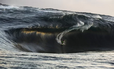 A dynamic surfer navigates a massive wave, capturing the thrill of surfing. This HD image serves as an inspiring desktop wallpaper for sports enthusiasts.