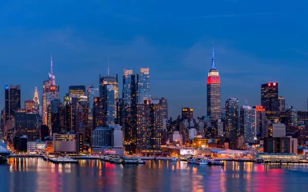 A stunning night view of Manhattan's skyline, showcasing skyscrapers reflecting on the water, capturing the vibrant city lights and energy of New York City.