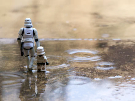 Two LEGO stormtroopers, one large and one small, standing on a wet, reflective surface. The humorous nature and the high-definition quality make it a great wallpaper, seamlessly blending Star Wars sci-fi with playful toy scenes.