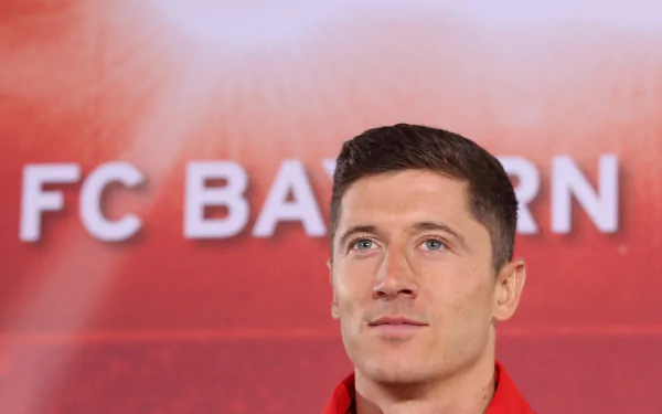 HD wallpaper of Polish soccer player Robert Lewandowski in front of an FC Bayern Munich sign, set against a red background.