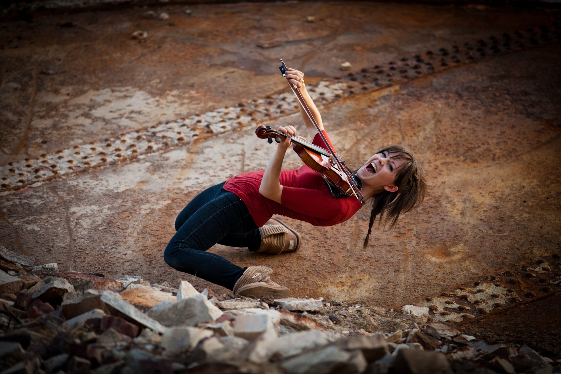 A dynamic 4K Ultra HD PC wallpaper featuring Lindsey Stirling playing the violin energetically against a textured, earthy background.