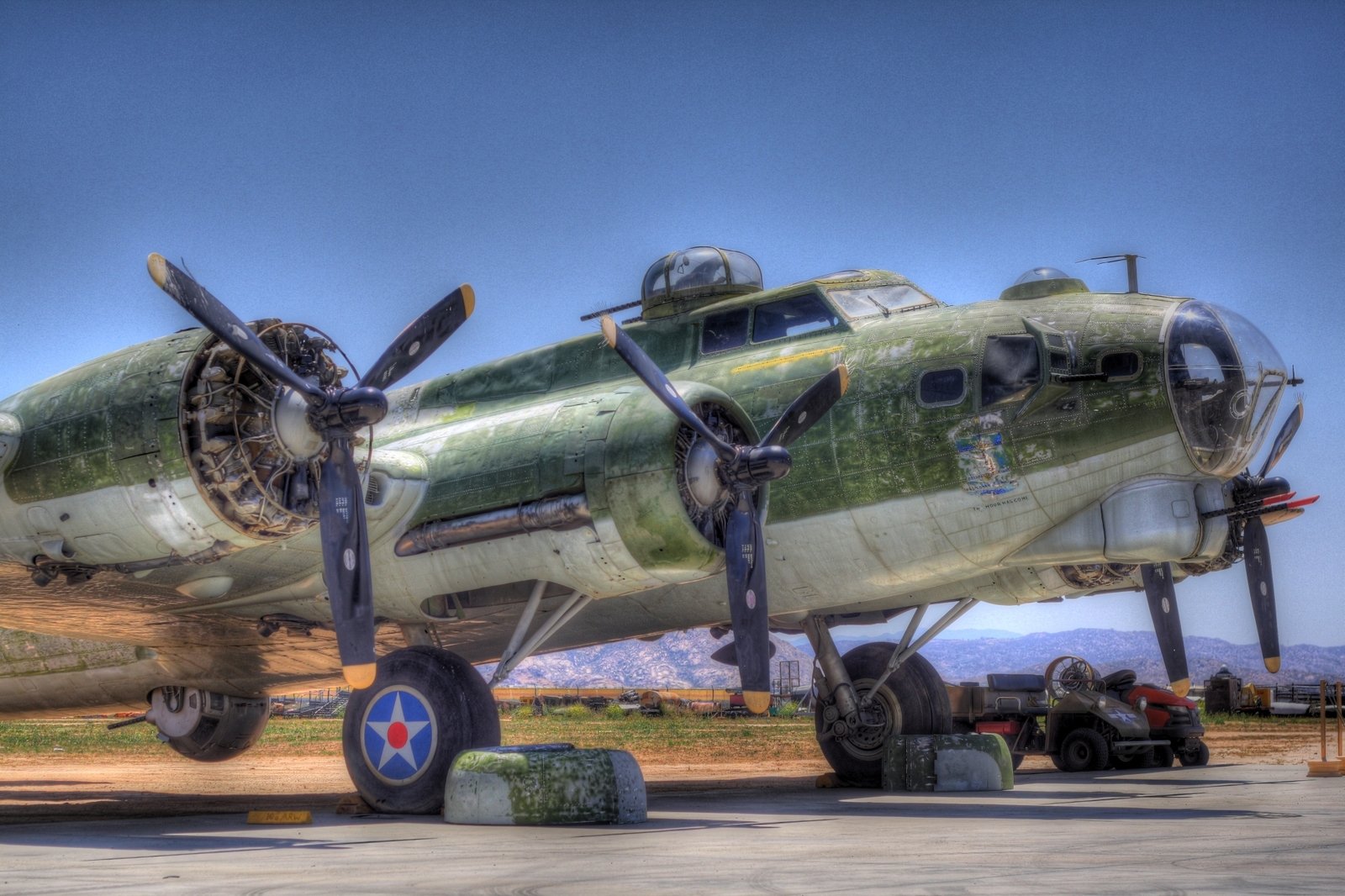 HD desktop wallpaper featuring a close-up view of a military Boeing B-17 Flying Fortress aircraft under clear blue skies.