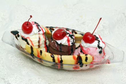 4K Ultra HD PC desktop wallpaper of a banana split: vanilla, chocolate and strawberry scoops with cherries and drizzled chocolate and strawberry syrup in a glass dish.